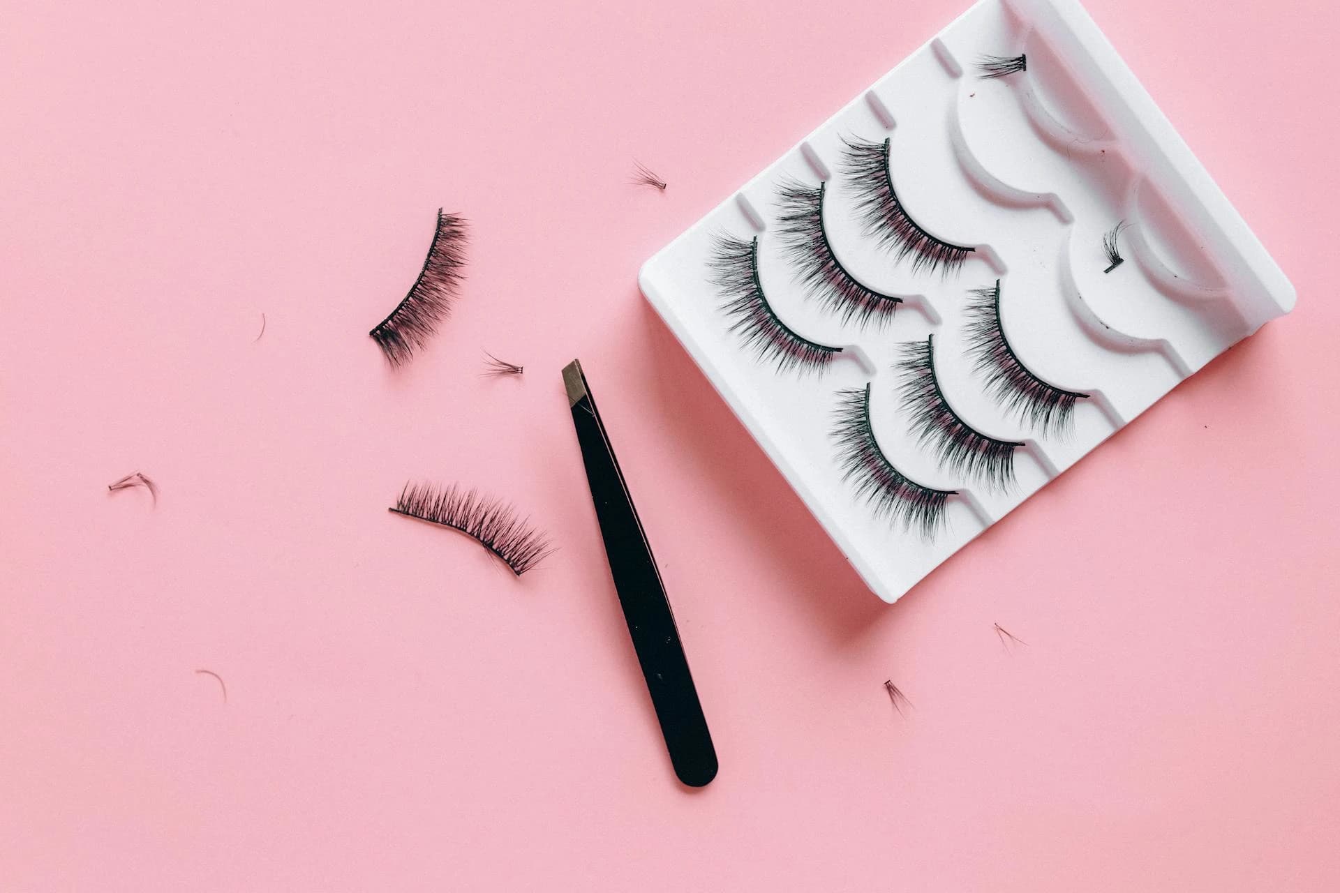 Lashes and beauty tools on a pink background